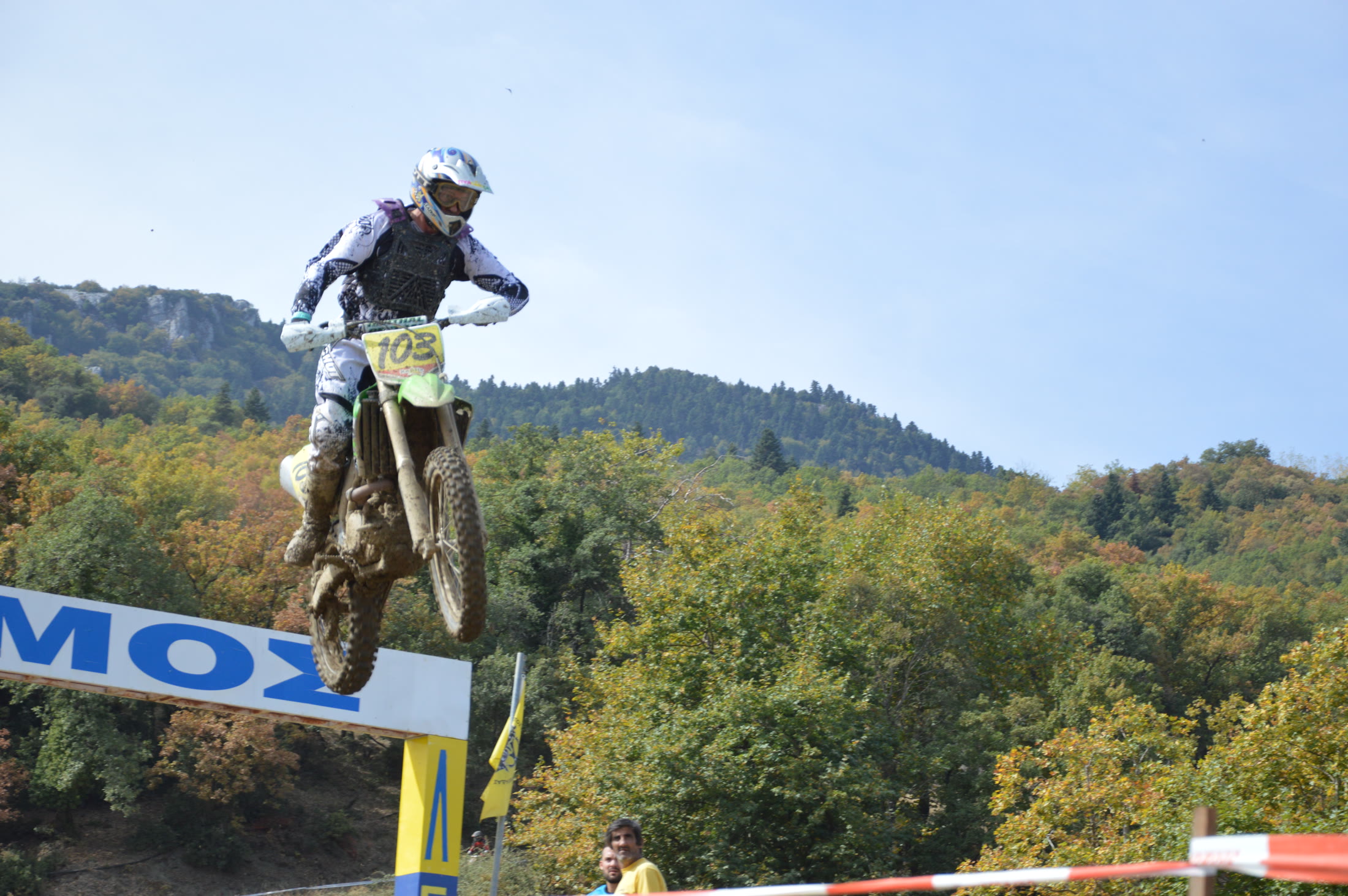 Enduro rider jumping against a mountain and forest backdrop
